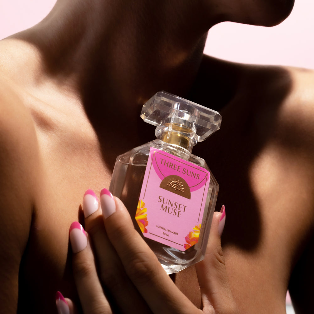 Sunset Muse luxury perfume bottle with gold spray lid, featuring a minimal Three Suns label, photographed on a neutral background included in the candle gift set.