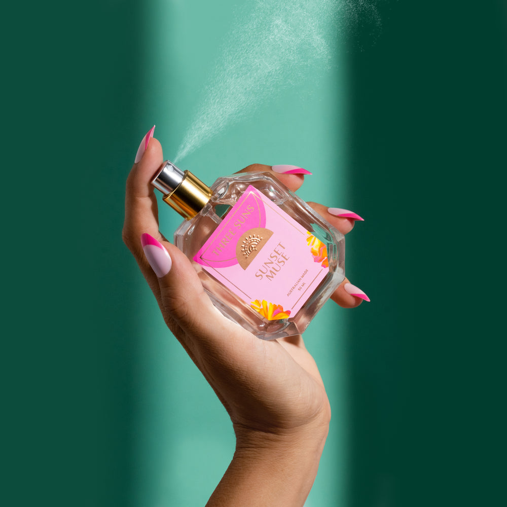 
                      
                        Luxury Sunset Muse perfume bottle with gold spray lid, minimal Three Suns label, and candle gift set on neutral background
                      
                    